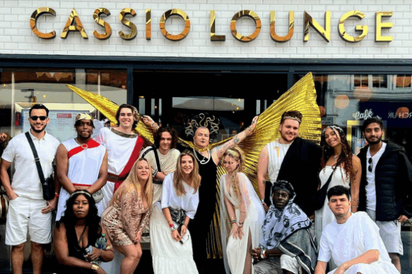 group of 16 people in costumes outside a cafe